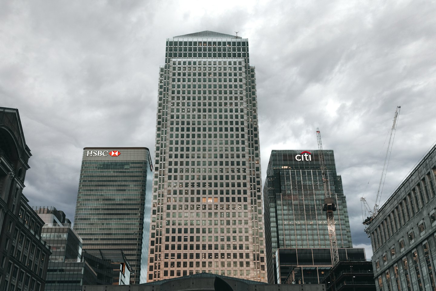 Modern skyscrapers ascend into a cloudy sky over a city.