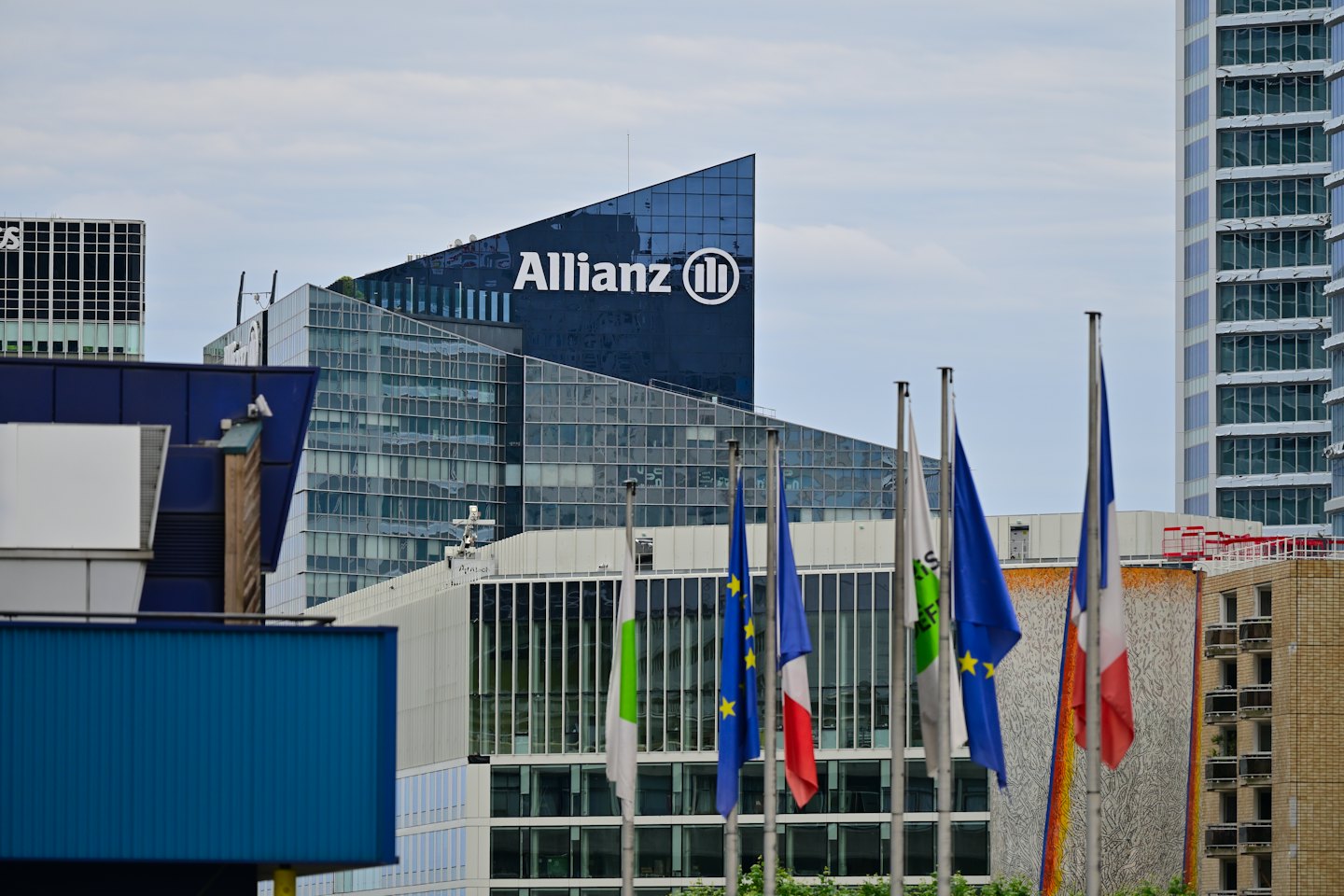 Allianz skyscraper with flags in a busy urban district.