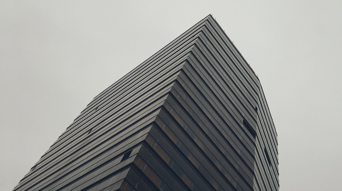 Modern high-rise building with angular lines against grey sky.